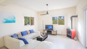 Uma sala de estar com sofá, mesa de centro, TV e lareira.