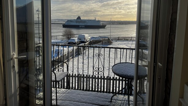 En balkon med udsigt til et stort skib, et hegn og et bord.
