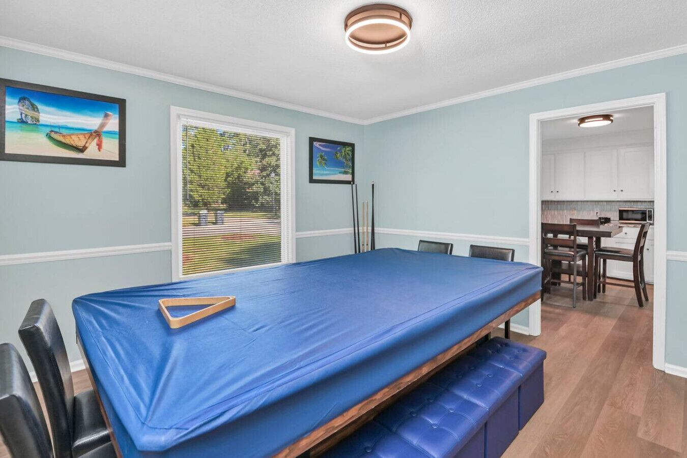 Ein Zimmer mit einem Etagenbett, einem Esstisch mit Stühlen, einer Küchenzeile und zwei gerahmten Bildern an der Wand.