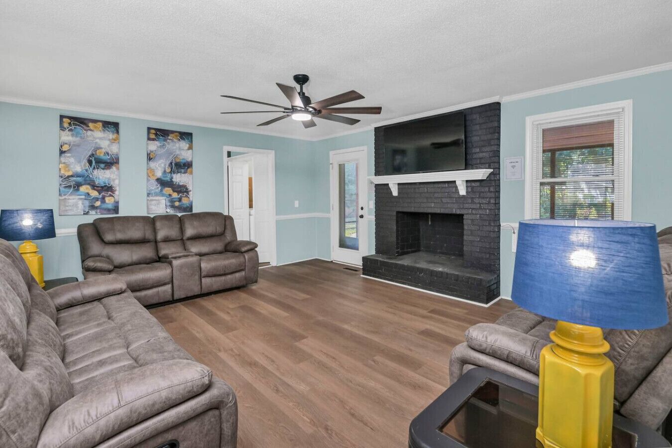 A living room with a fireplace, a ceiling fan, and two sofas.