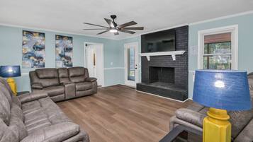 A living room with a fireplace, a ceiling fan, and two sofas.