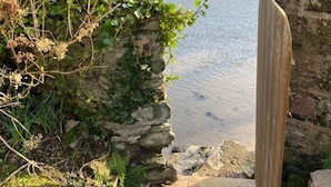 Eine steine Mauer mit einem hölzernen Tor, das zu einem Fluss führt.