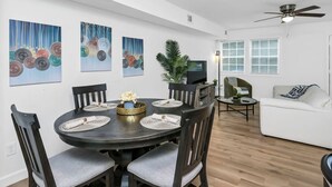 A dining area with a round table, chairs, and artwork on the walls. - Stay West Side | 2 BR | Minutes from Downtown (West Columbia)