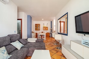 A living room with a sofa, TV, and a dining area with a table and chairs.