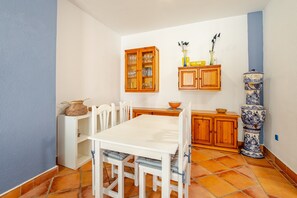A compact kitchen with a white table and chairs, wooden cabinets, and a blue wall.