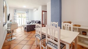 Un comedor con una mesa y sillas blancas, un sofá y un televisor.