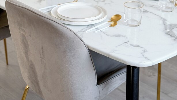 Une table à manger dressée avec des assiettes, des verres et un vase de fleurs.