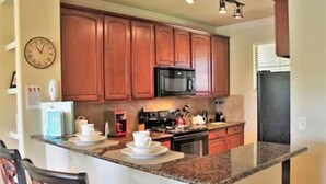 A kitchen with wooden cabinets, a microwave, and a coffee station. - Pool view condo minutes to Disney World (Davenport)