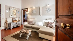 Una sala de estar con un sofá, una puerta de madera y un espejo con una lámpara.