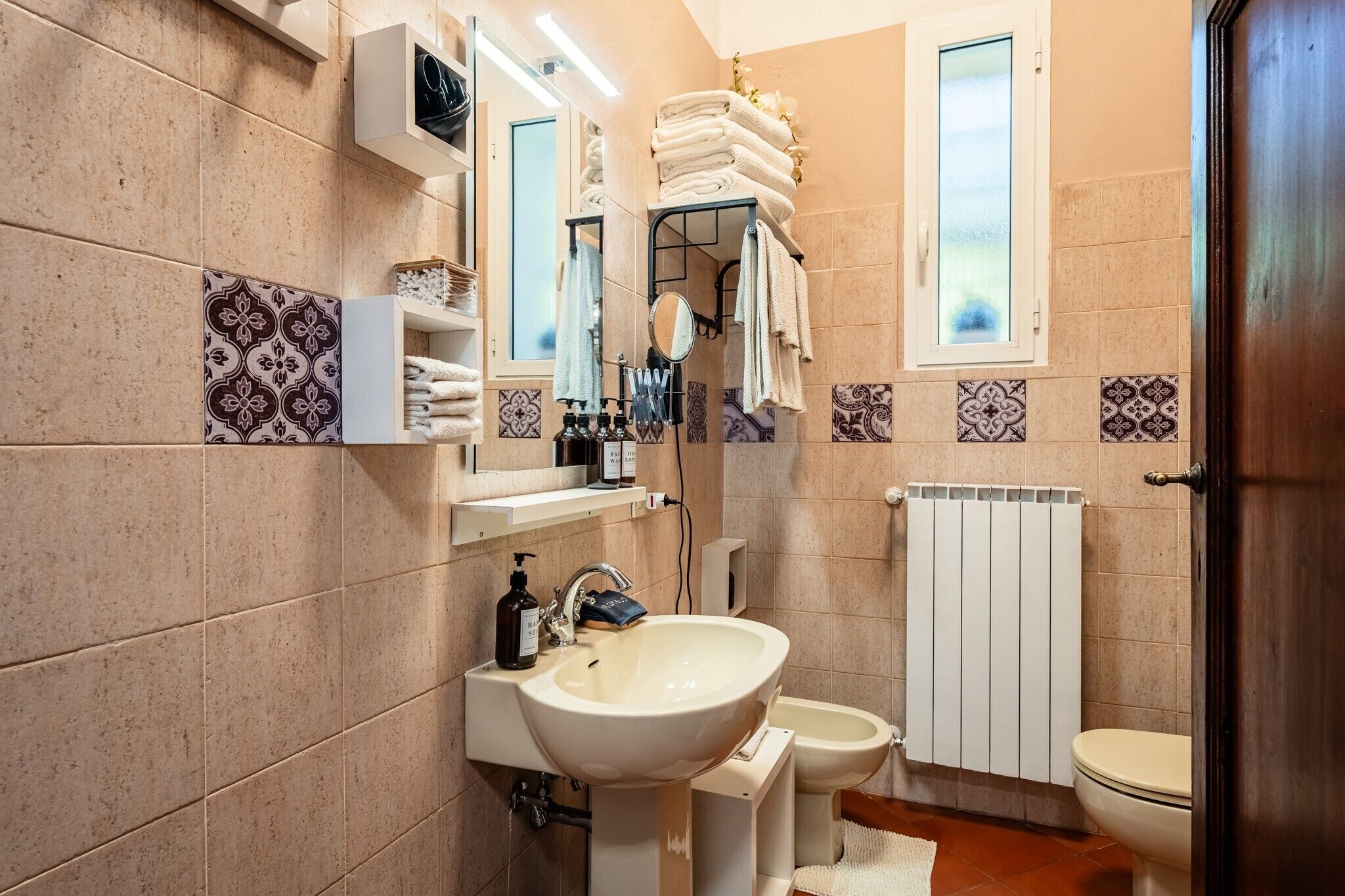 Une salle de bain équipée d’un lavabo, d’un miroir, d’un porte-serviettes et de toilettes.
