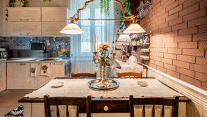 Una cocina con una mesa de comedor, plantas colgantes y una pared de ladrillo.