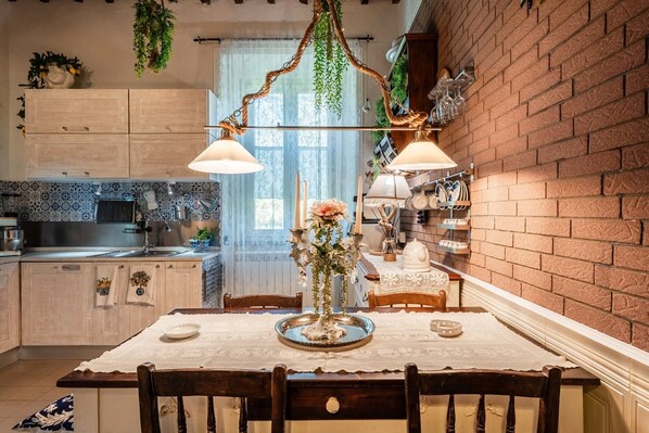 A kitchen with a dining table, hanging plants, and a brick wall. - La Maison de Jardin – Dog-Friendly Suite at Villa Mon Paradis (Lucca)
