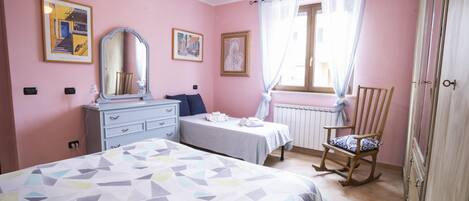 A bedroom with a bed, a dresser, a chair, and a window with curtains.