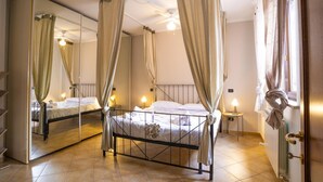 A four-poster bed with a canopy, a bedside table with a lamp, and a mirror on the wall.