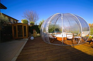 A transparent dome structure with seating inside, a wooden deck, and a small shed in the background. - Villa Patty With 4 Bedrooms and 2 Bathrooms (Assisi)