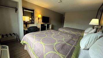 A hotel room with a large bed, a desk with a chair, a television, and a lamp.