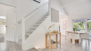 Un intérieur moderne avec un escalier, un coin repas et une vue dégagée grâce à de grandes fenêtres.