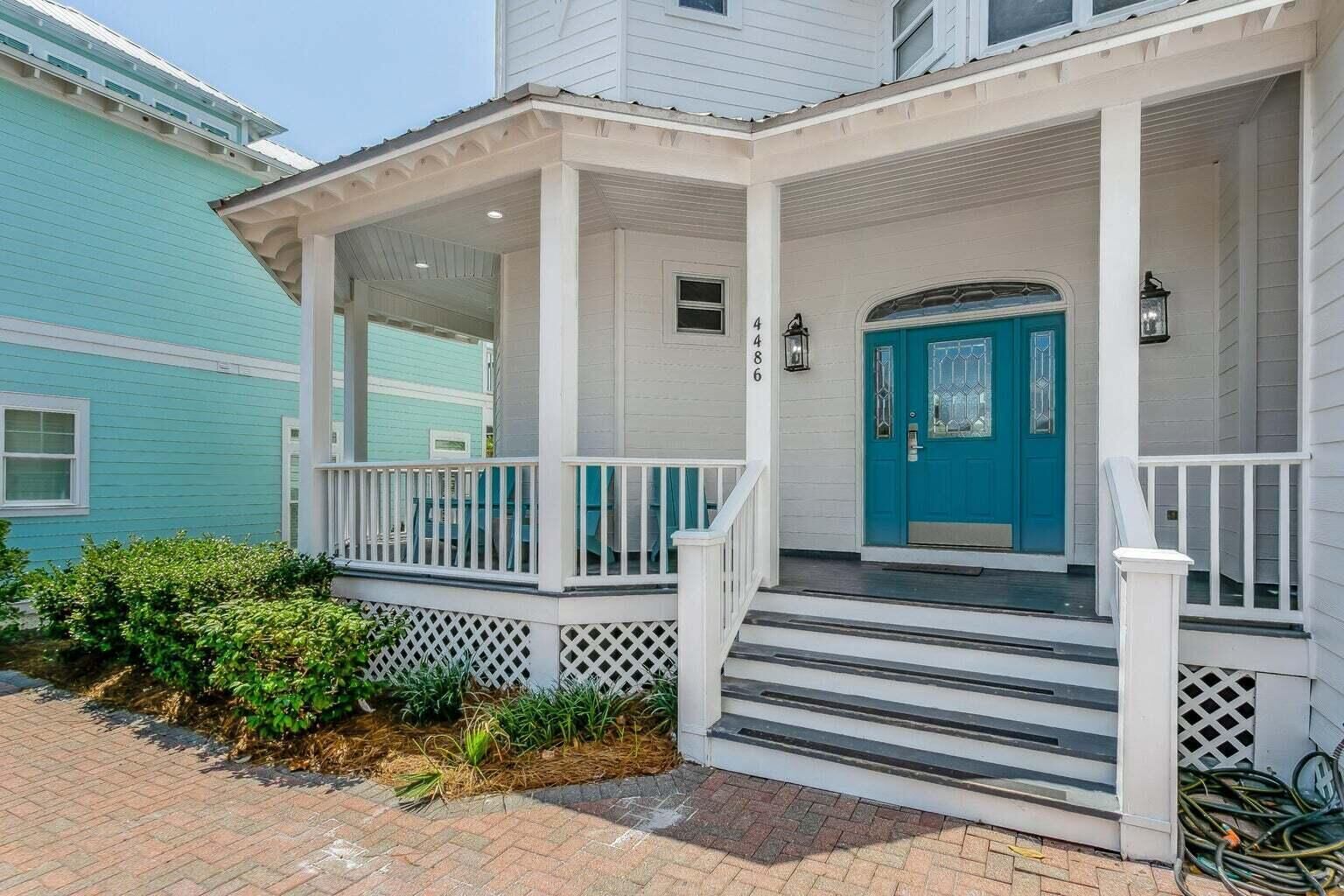 A two-story house with a porch, a blue door, and a mailbox.