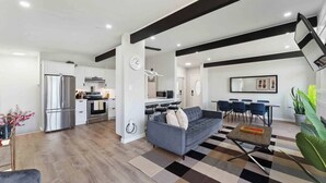 Una sala de estar moderna con sofá, mesa de centro y zona de comedor.