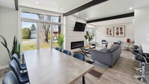 Una sala moderna con chimenea, un sofá y un comedor con sillas.