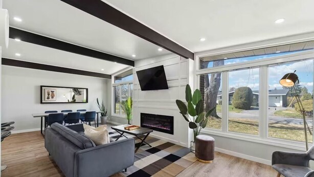 Una sala de estar moderna con un sofá gris, una mesa de centro, una chimenea y un ventanal con vistas al exterior.