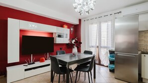 A modern kitchen with a built-in refrigerator, a dining table with chairs, a flat-screen TV, and a decorative vase. - Casa Luna with Private Terrace, Wi-Fi and Air Conditioning (Balestrate)