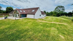 Ein modernes Haus mit geneigtem Dach, einem großen Rasen und blauem Himmel.