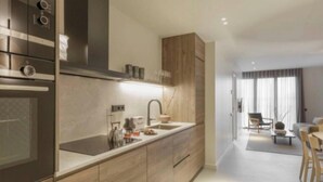 Una cocina moderna con armarios de madera, horno empotrado y una isla grande con fregadero.