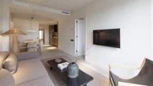 Una sala de estar moderna con un sofá, una mesa de centro y un televisor de pantalla plana montado en la pared.