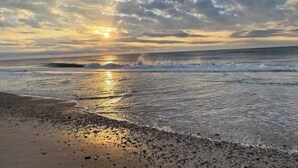 Ein Strand mit Wellen und einem Sonnenuntergang.