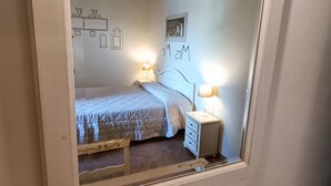 A bedroom with a bed, bedside tables, a lamp, a mirror, and a small decorative item on a dresser.