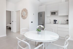 A modern kitchen with white cabinetry, a stainless steel refrigerator, a microwave, and a coffee maker.