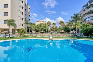 Une piscine entourée de palmiers et un immeuble à plusieurs étages.