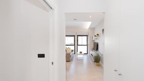 Un pasillo que da a una sala de estar con un sofá, una mesita y un televisor.