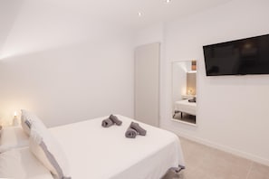 Une chambre d’hôtel avec un lit, une télévision, un miroir et une table de chevet avec une lampe.