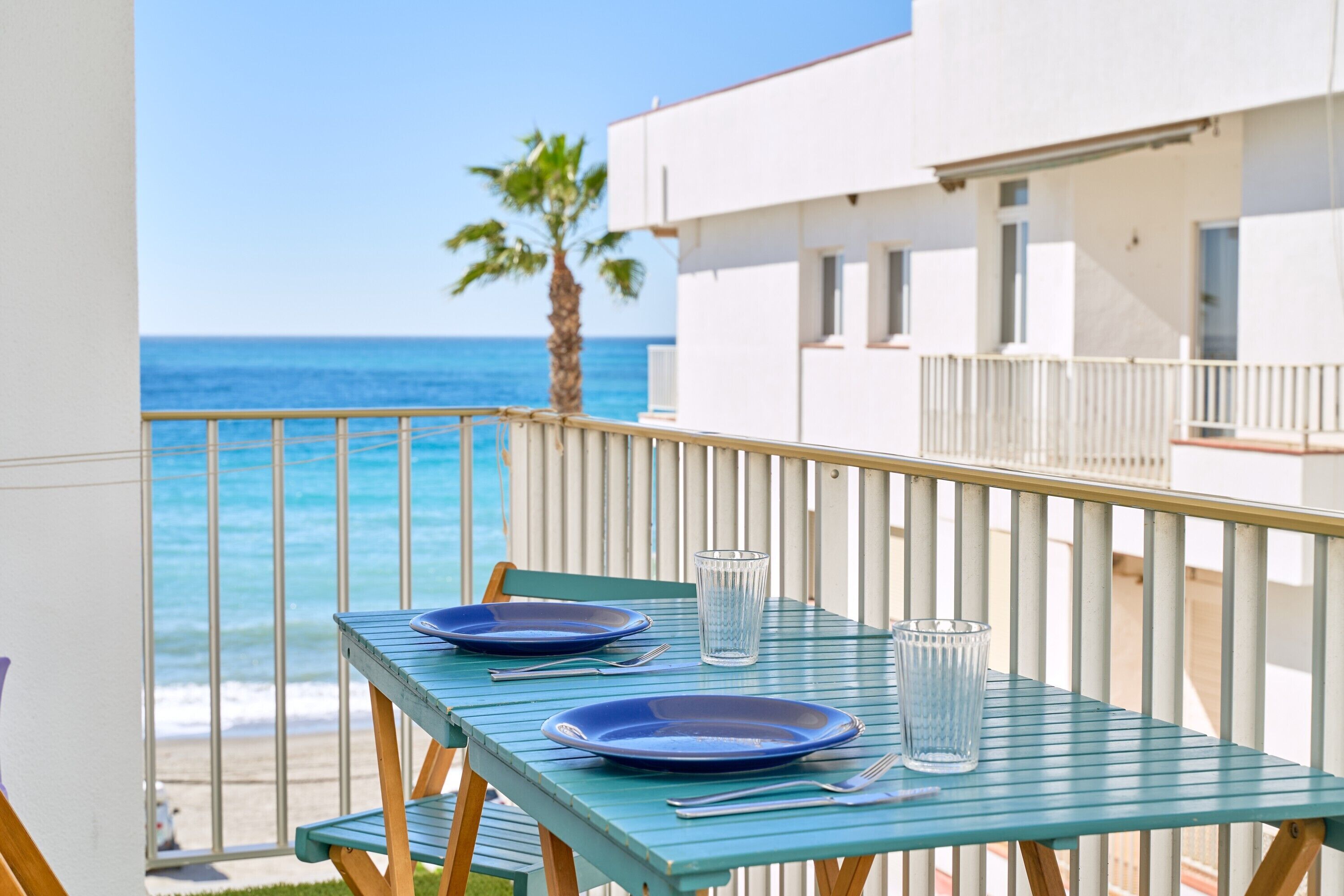 Een balkon met een tafel gedekt voor twee personen, met uitzicht op zee.