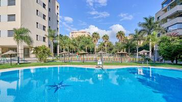 Una piscina rodeada de palmeras y un edificio de varios pisos.