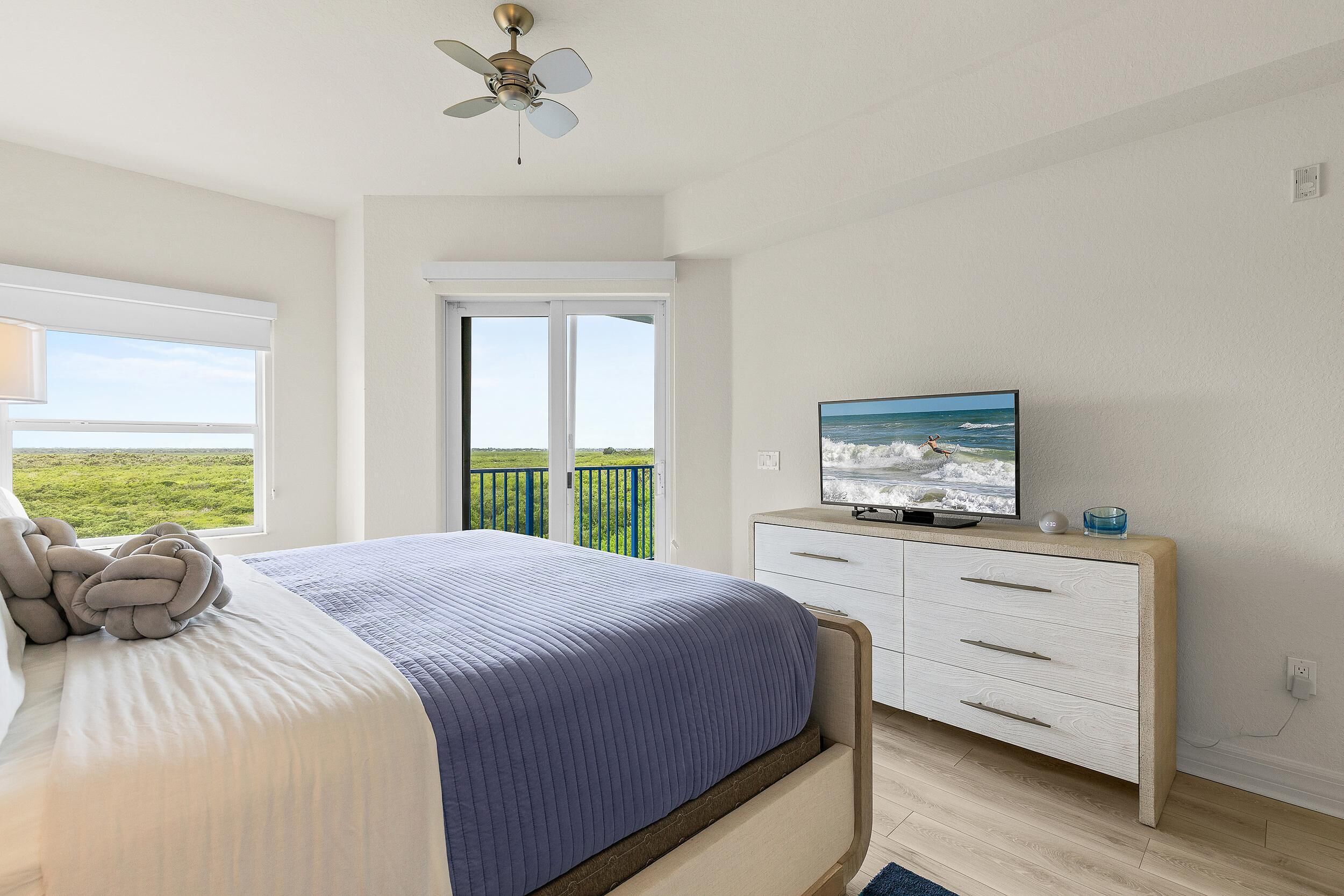 Un dormitorio con cama, televisión, cómoda y balcón con vistas.