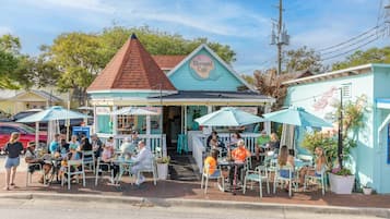 A seaside café with outdoor seating and a distinctive mermaid-themed sign.