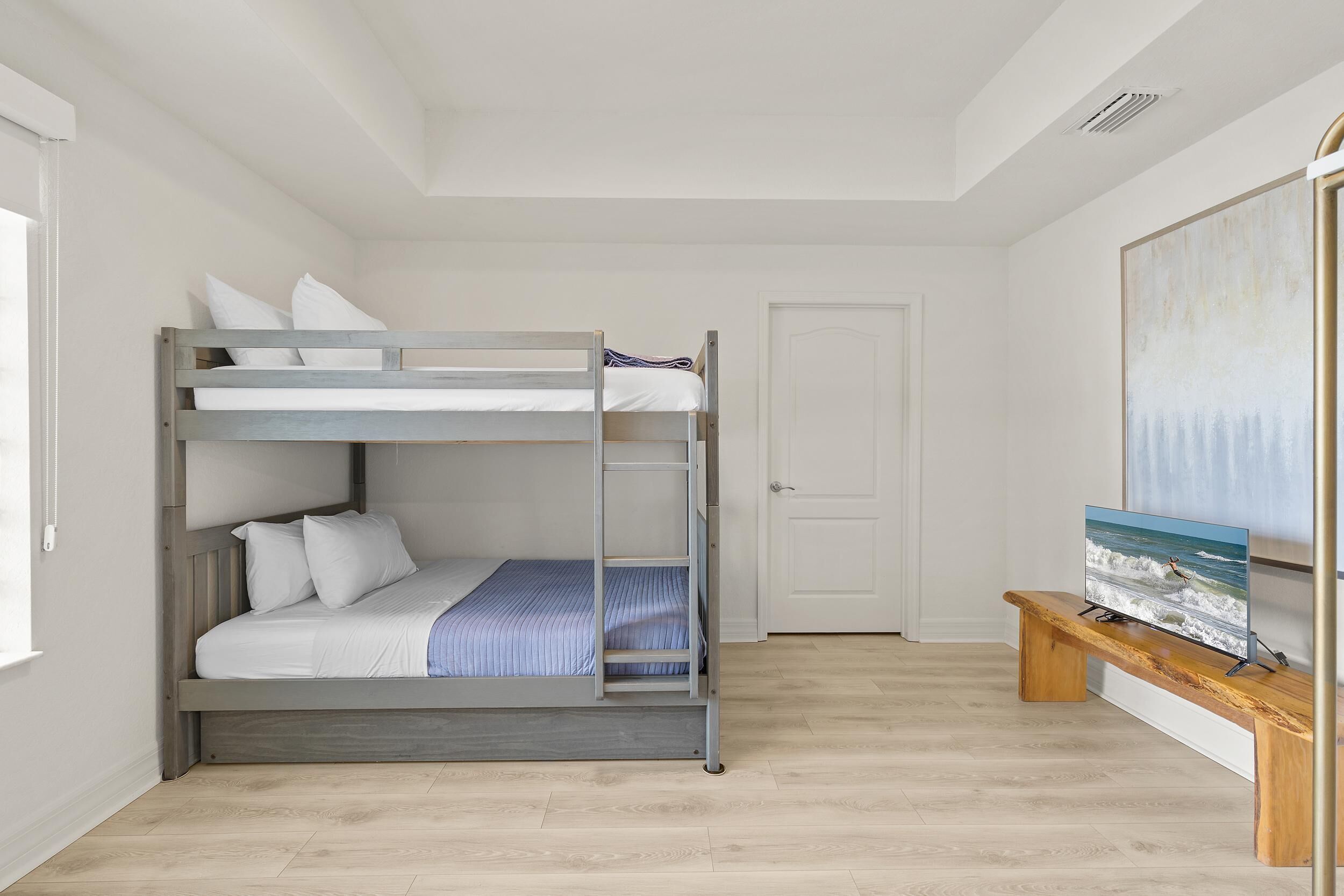 A bunk bed in a room with a wooden bench and a painting on the wall.