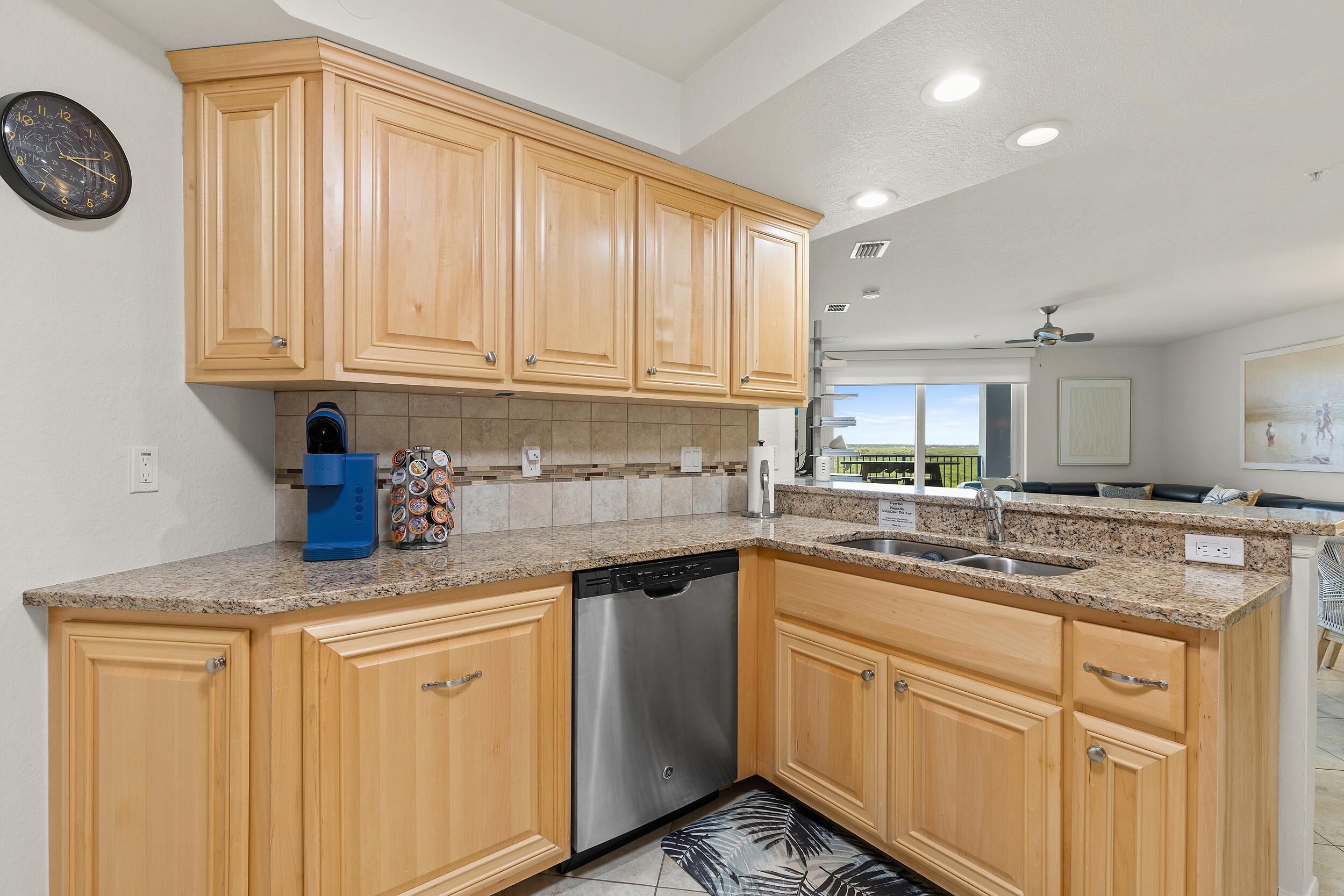 A kitchen with wooden cabinets, granite countertops, a dishwasher, and a coffee maker.