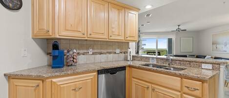 A kitchen with wooden cabinets, granite countertops, a dishwasher, and a coffee maker.