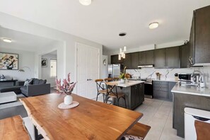 Une cuisine moderne avec des meubles de couleur sombre, des appareils en acier inoxydable et un îlot central.
