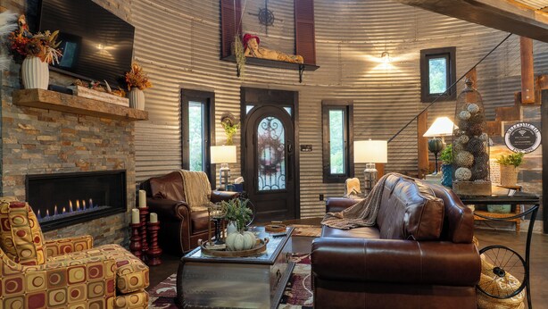 A cozy living room with a fireplace, leather furniture, and a stone wall.