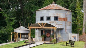 A rustic, cylindrical metal building with a wooden porch and a small attached structure.