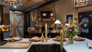 A dining table set with yellow napkins, a bottle of antibacterial hand sanitizer, and a vase of flowers.
