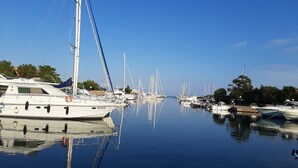 Una marina con diverse barche a vela ormeggiate, acqua calma e cielo sereno.