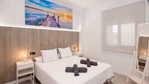 A hotel room with a bed, nightstands, a painting, a window, and a mirror. - Apartment '2-Bed Antares' with Shared Pool, Wi-Fi, and Air Conditioning (Torre del Mar)