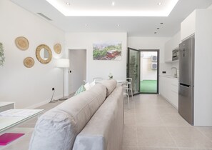 A modern living area with a sofa, dining table, and kitchen with a refrigerator.