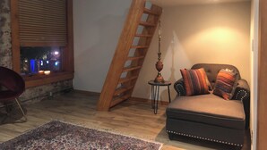 Un accogliente soggiorno con una scala in legno, una panca imbottita, un tavolino con una lampada e una vista dalla finestra.